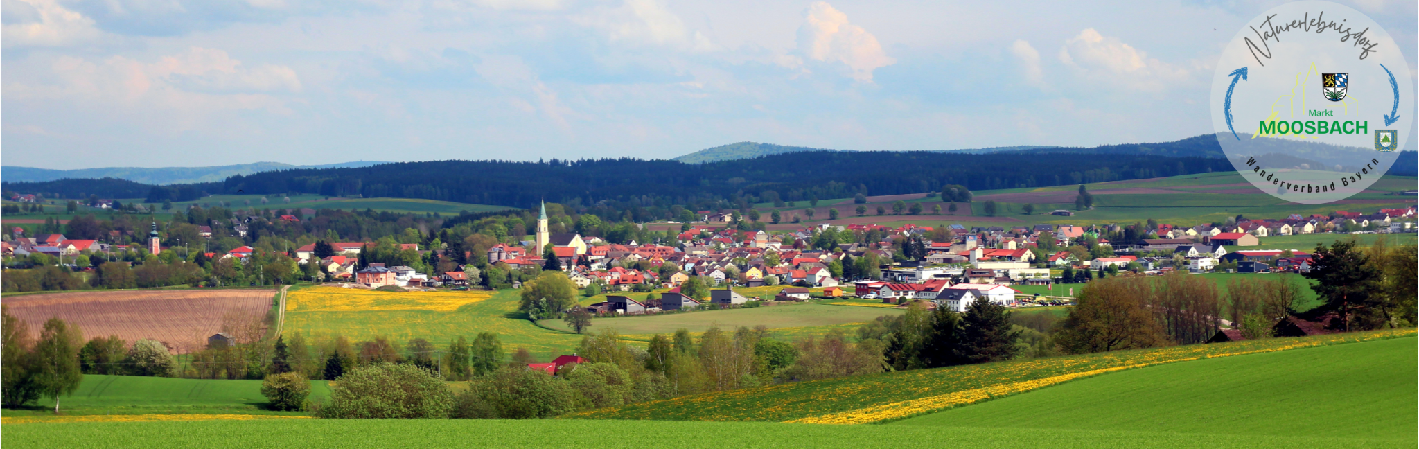 Panoramaaufnahme von Moosbach mit der Silhouette des Marktes umgeben von freier Natur mit Wäldern, Wiesen und Feldern
