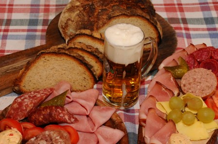 Bild einer echten oberpfälzer Brotzeit mit frisch aufgeschnittenem Brot, einer Wurstplatte und einem Glas Bier oder Zoigl